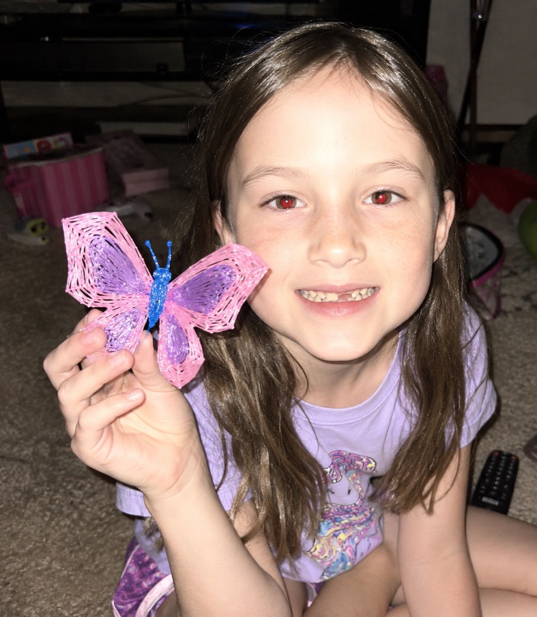 Une enfant montre fièrement un papillon en 3D réalisé au stylo Pen'Up 3D